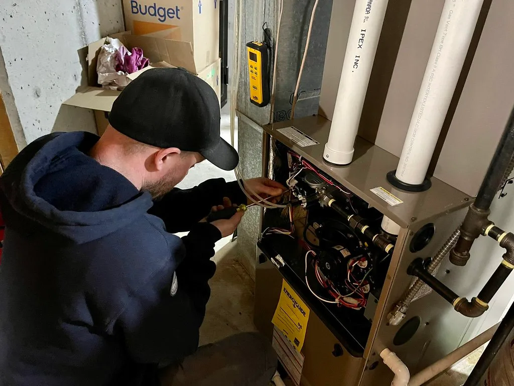 Technician replacing a furnace control board with hand tools