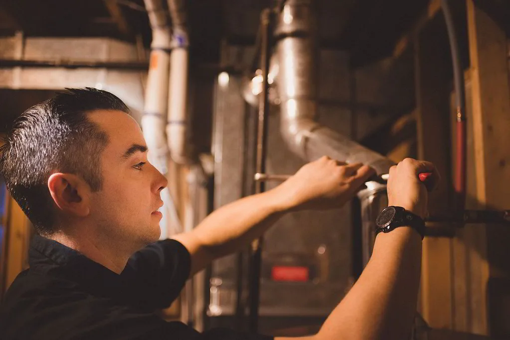 Technician brazing copper refrigerant lines during an installation