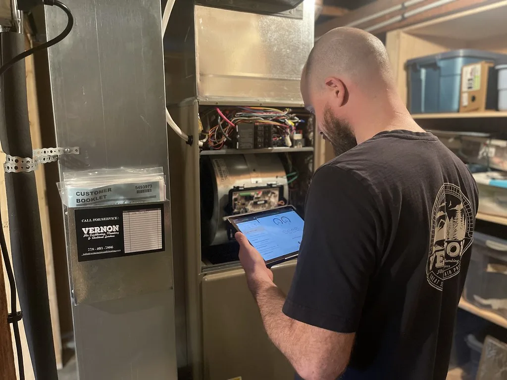 Technician servicing a residential gas furnace with the cabinet open
