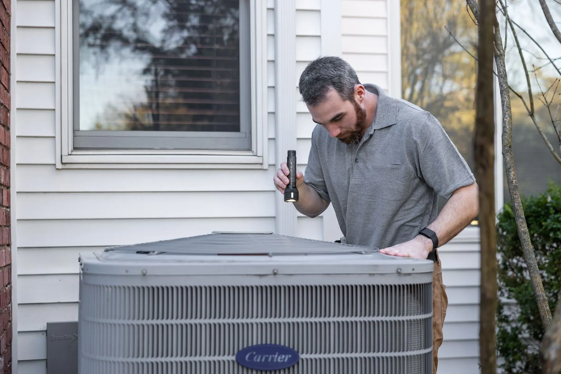HVAC technician servicing equipment outside a home