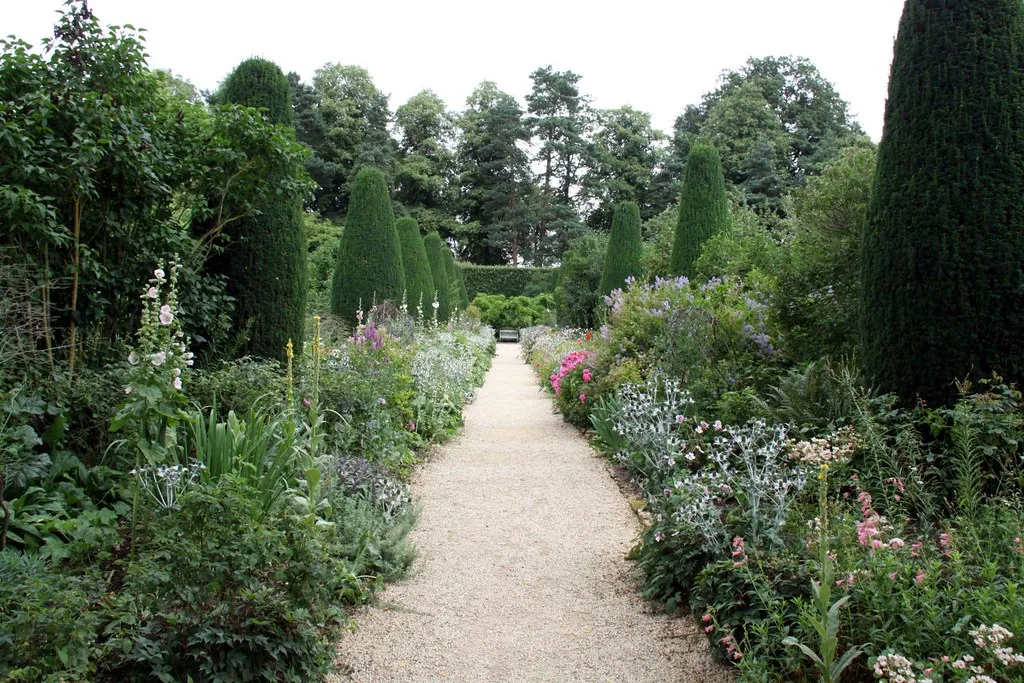 Manicured garden room with topiary and a wooden bench