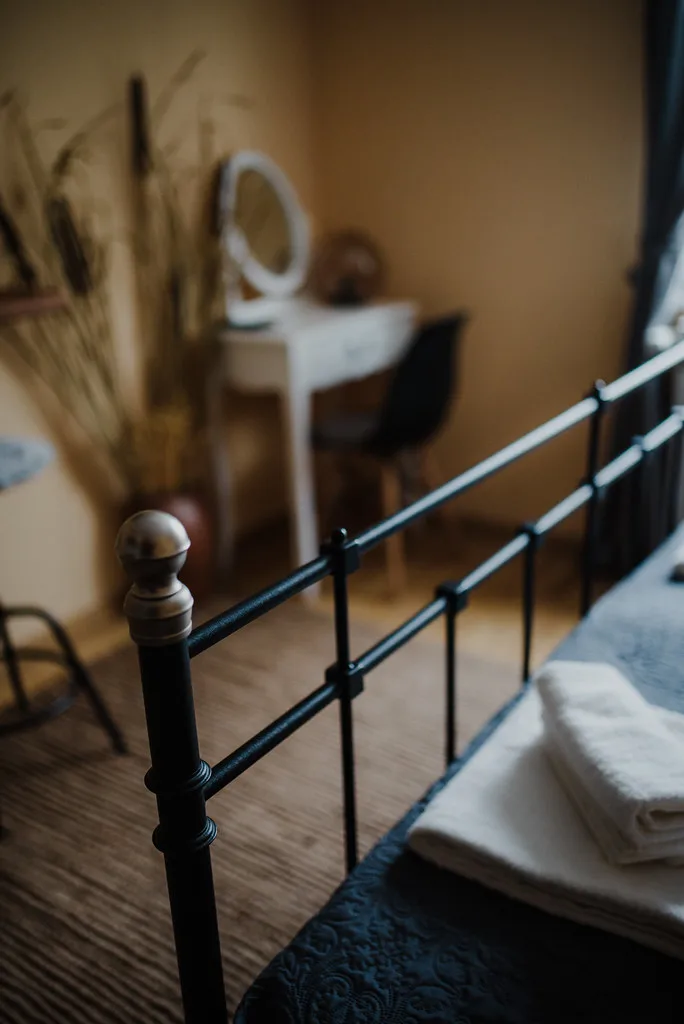 Sunlit guest room with a vintage brass bed and a wooden vanity