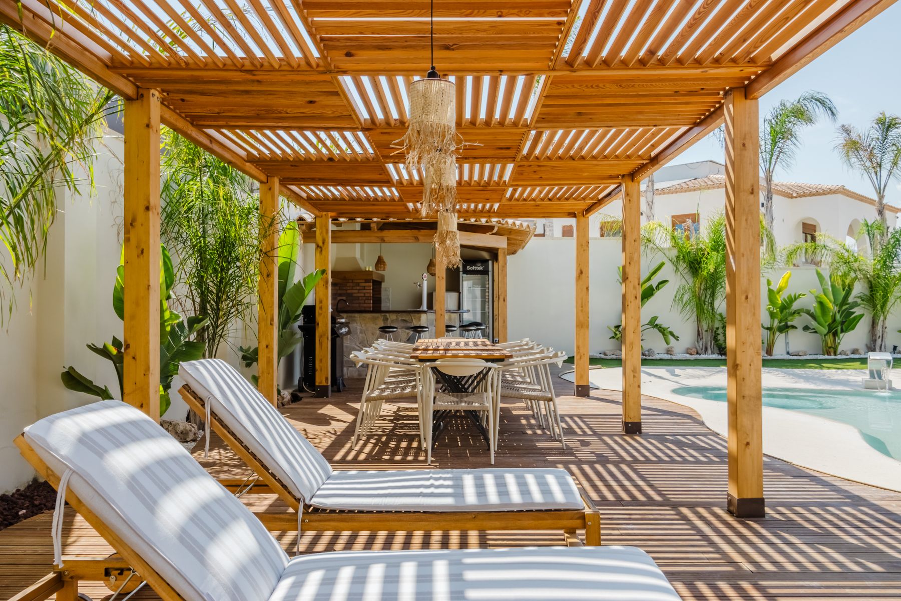 Timber pergola shading an outdoor dining space beside a garden pool