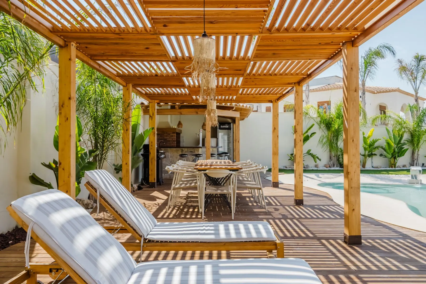 Timber pergola shading an outdoor dining space beside a garden pool